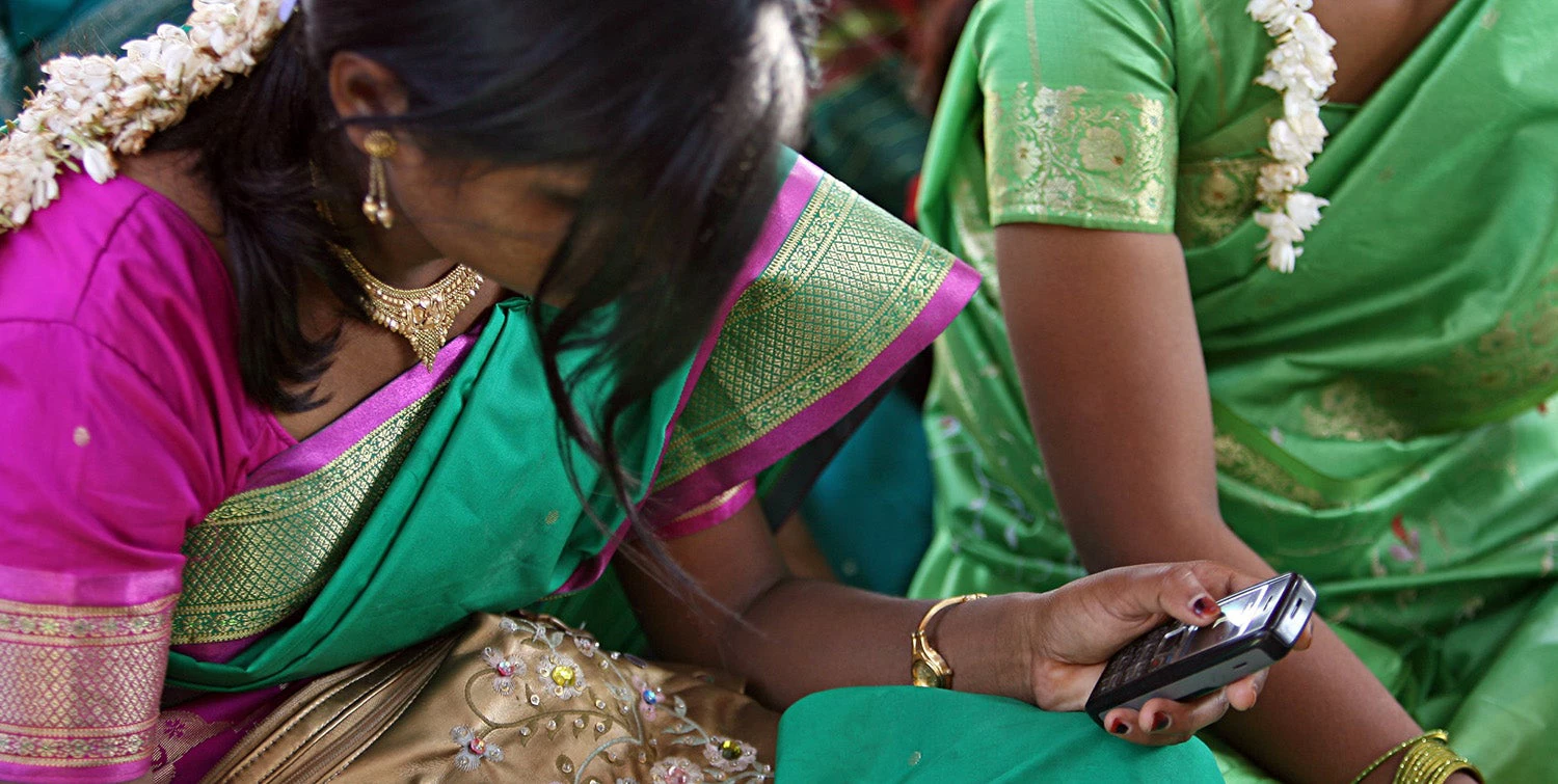 Young women look at their cellphone during a community meeting.