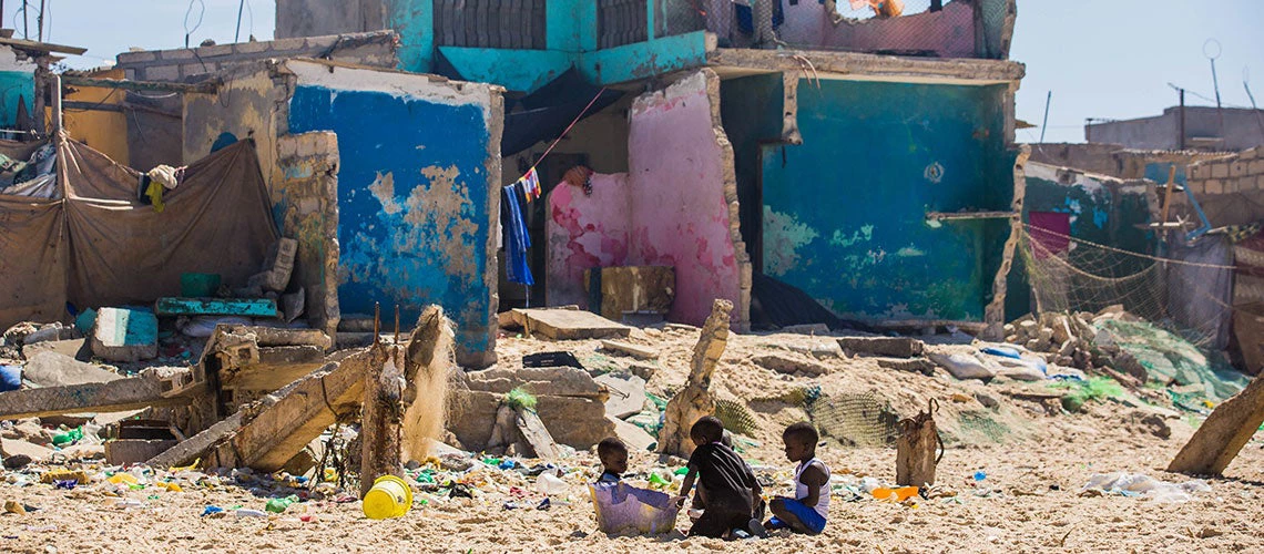 Dans le quartier de Santhiaba, des enfants jouent sur la plage en face d'une maison détruite.