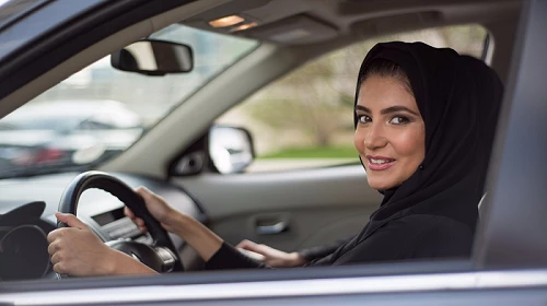 Woman wearing black head scarf behind the wheel of a car
