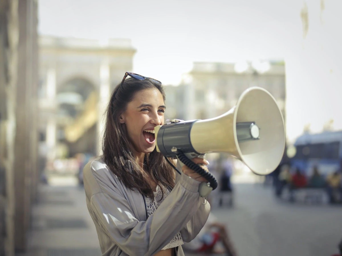 A woman is eagerly speaking into a megaphone