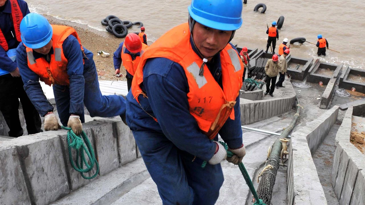 Workers drag a submarine cable onshore in Shengsi Island, Zhoushan City, east China s Zhejiang Province, March 16, 2011