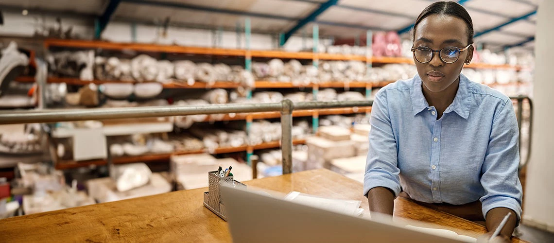 Young woman working with a laptop at her warehouse desk. | © shutterstock.com