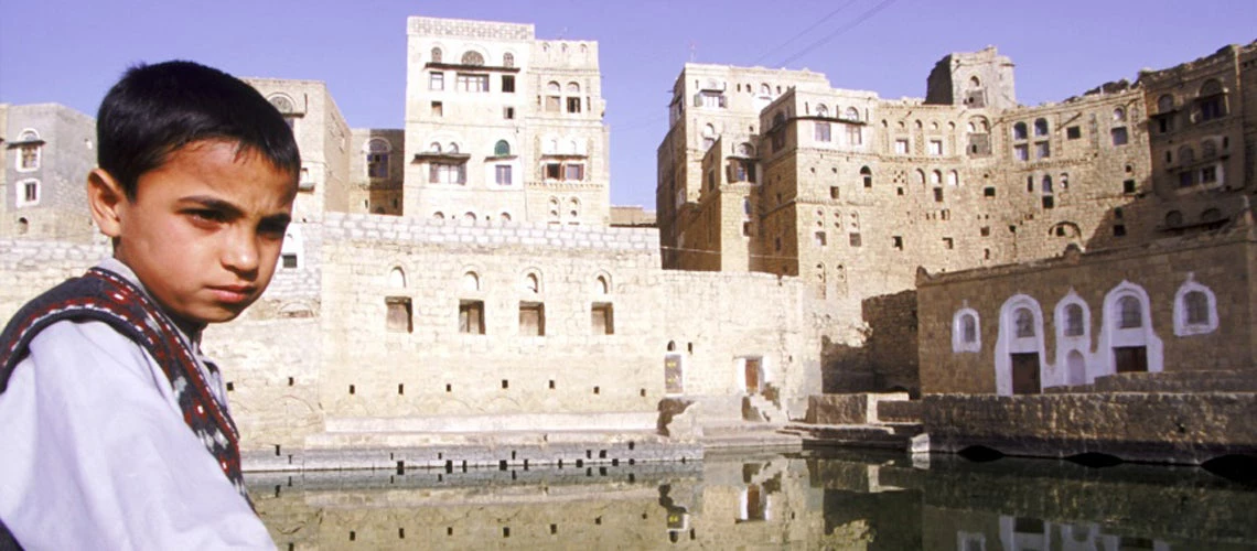 Young boy sitting by centuries old cistern in Yemeni town of Hababa.