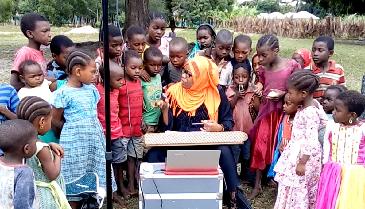 Un membre de l'équipe d'Open Cities Zanzibar explique le processus de cartographie aux enfants d'une communauté faisant partie du projet.